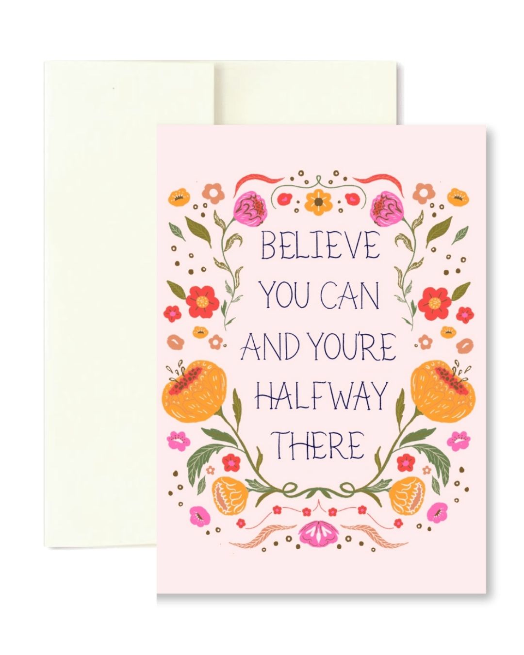 A pink greeting card with a floral wreath illustration and the phrase 'BELIEVE YOU CAN AND YOURE HALFWAY THERE' in dark blue lettering, shown with a cream envelope behind it on a white background.