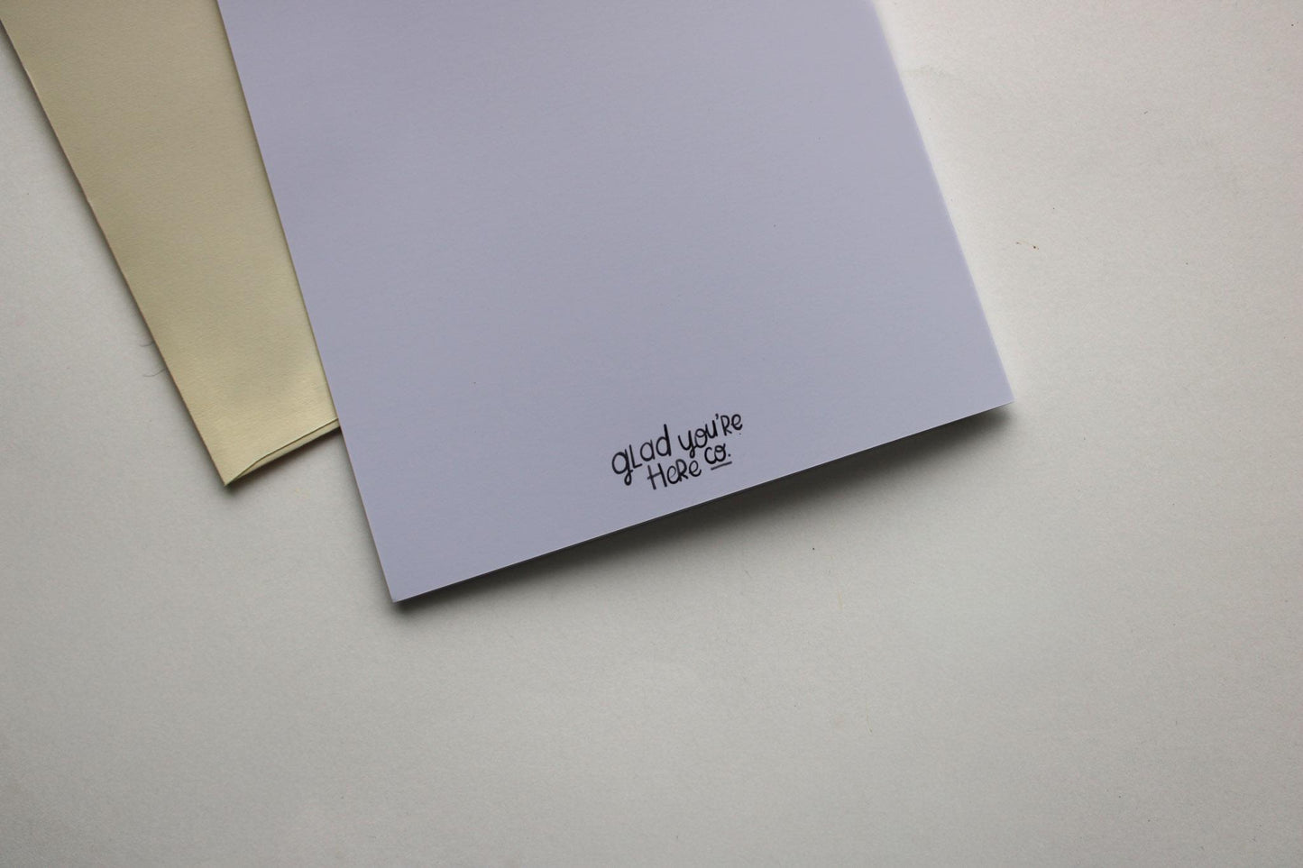 Two greeting cards, one beige and one purple, on a light gray surface.