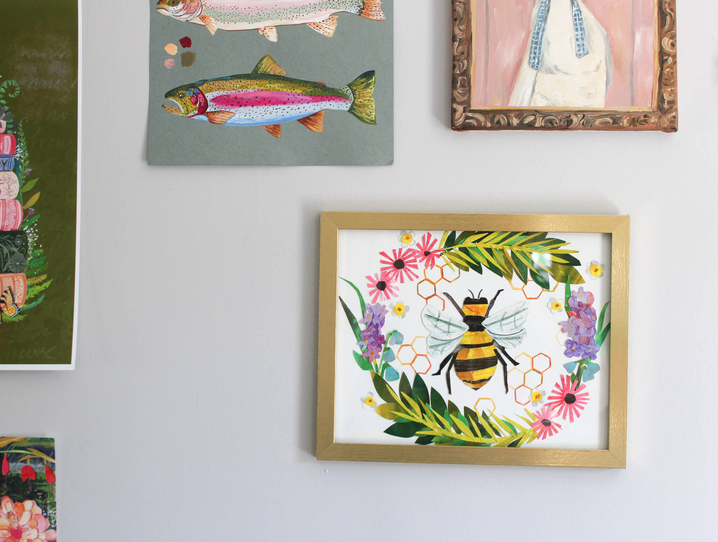 Framed artwork of a bee and flowers on a wall with other framed pictures.