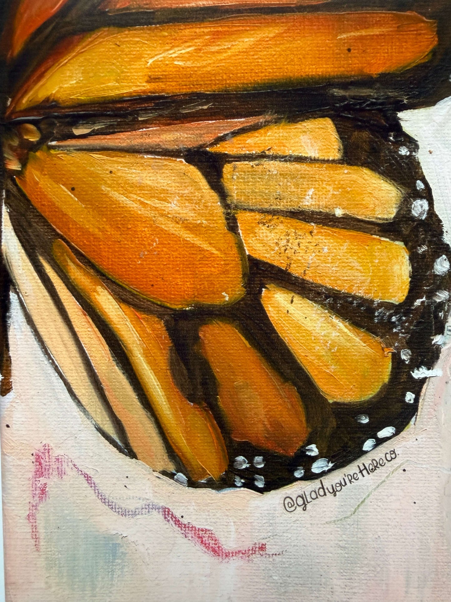 A close-up painted butterfly wing detail with orange and yellow wing sections outlined in black, on a light textured background. A small artist signature is visible near the lower right.