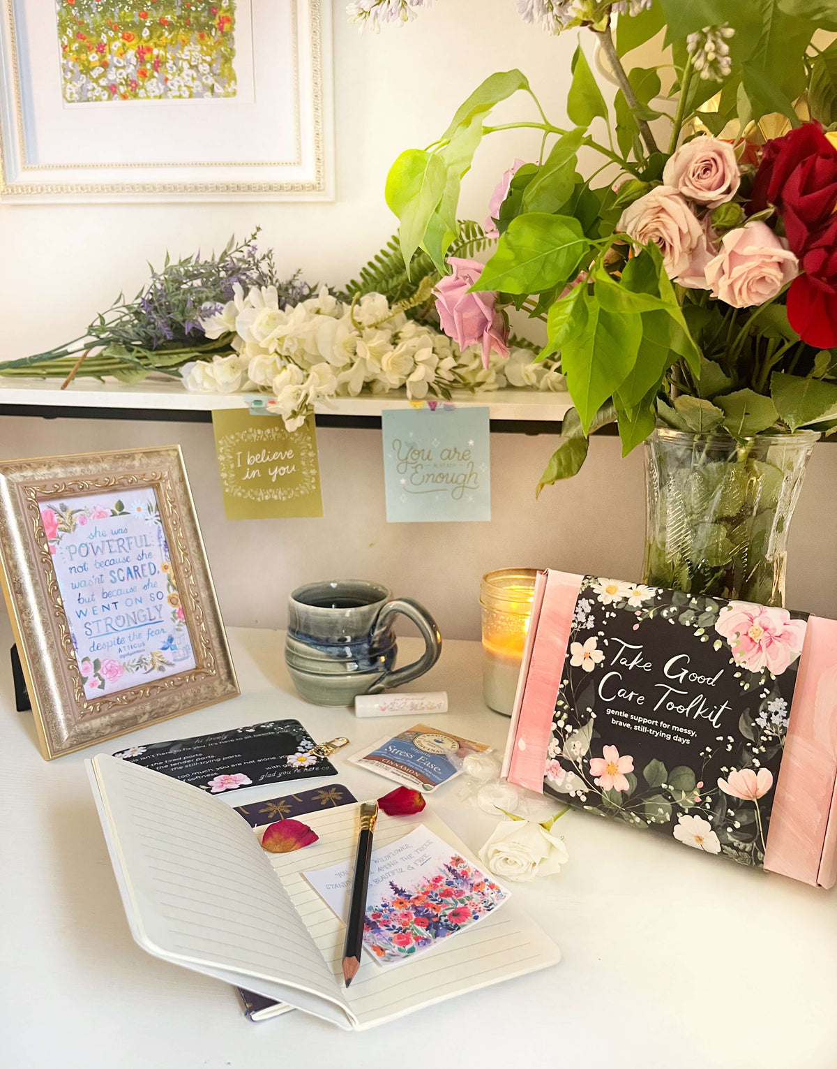 Desk with notebook, mug, cards, and flowers in a home office setting