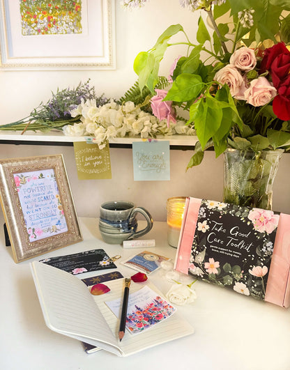 Desk with notebook, mug, cards, and flowers in a home office setting