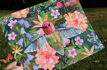Colorful patchwork art piece with a hummingbird and flowers on a grassy background
