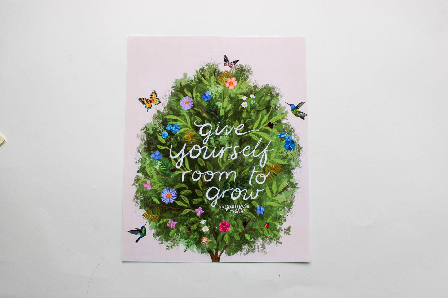 Card with a green wreath and flowers on a pink background with text 'Give yourself room to grow'.