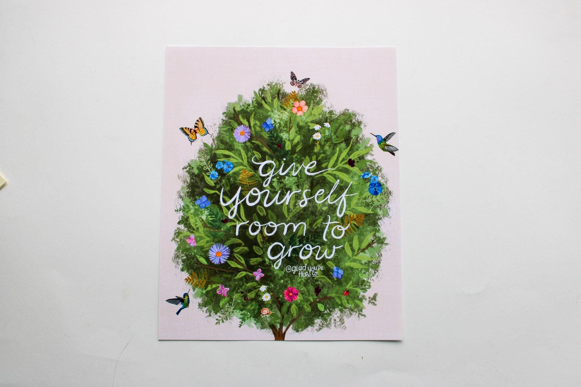 Card with a green wreath and flowers on a pink background with text 'Give yourself room to grow'.