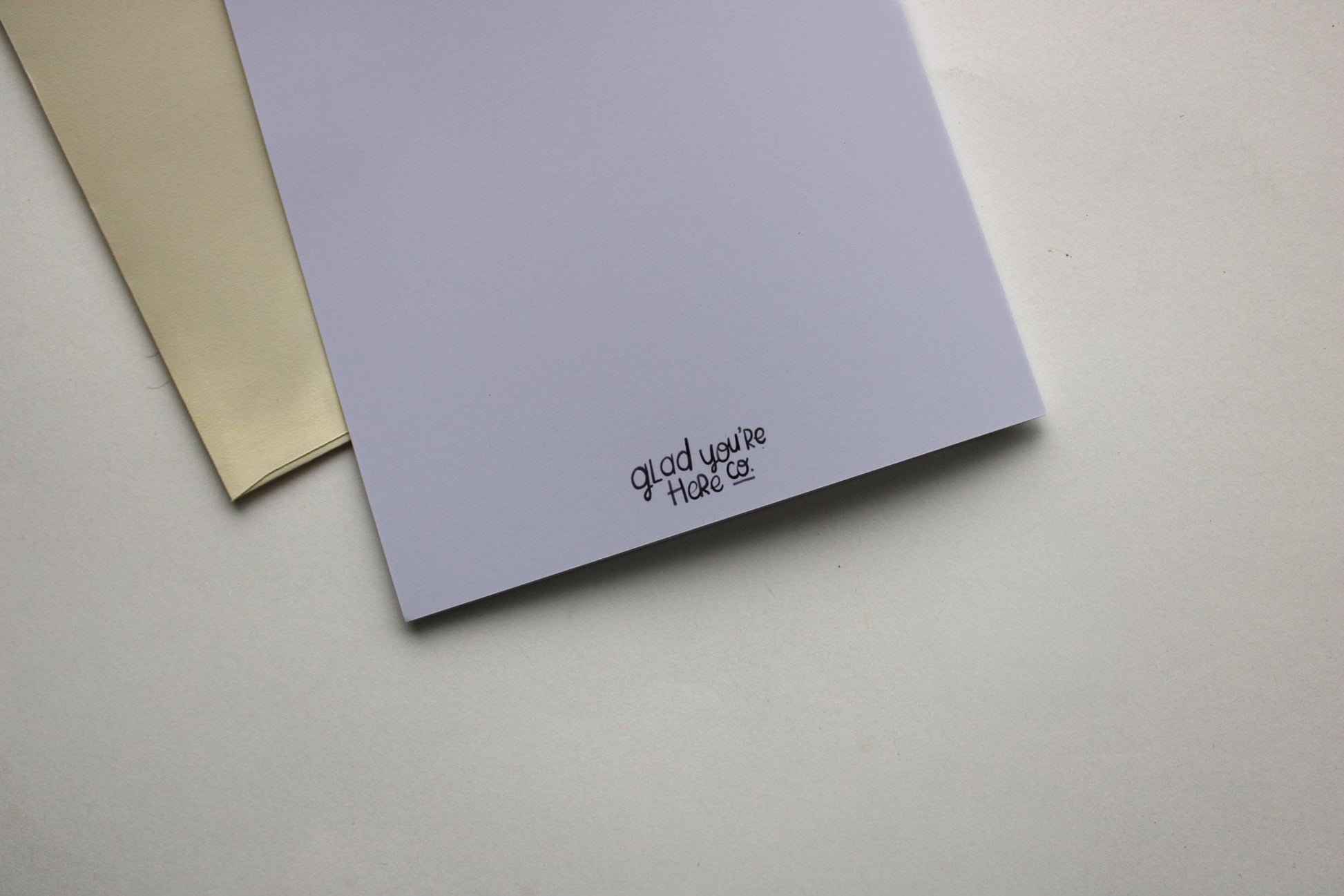 Two greeting cards, one beige and one purple, on a light gray surface.