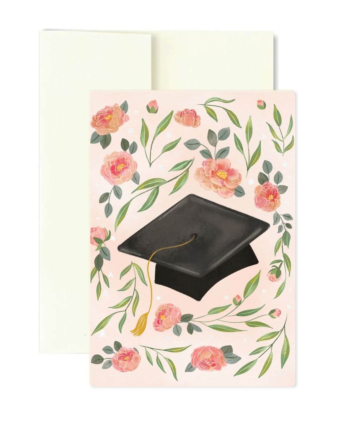 A graduation-themed greeting card with a black mortarboard cap illustration surrounded by pink flowers and green leaves on a pale blush background, shown with a white envelope behind it.