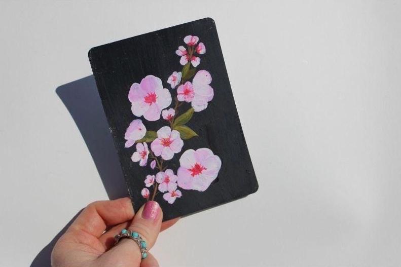 Black cardholder with pink floral design held by a hand against a light gray background