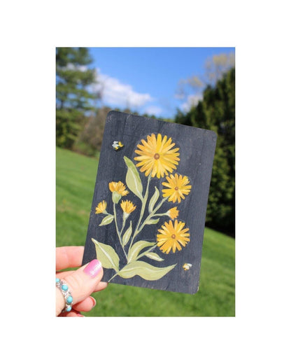 Hand holding a card with floral design outdoors