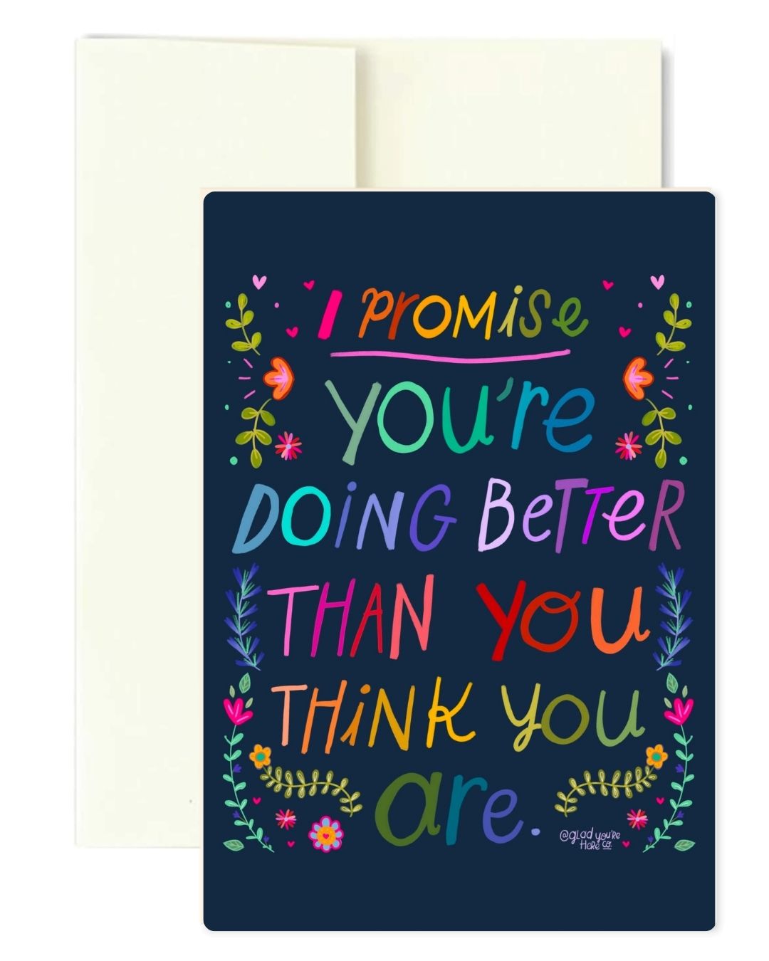 A navy blue greeting card with colorful hand-lettered text reading 'I promise you're doing better than you think you are.' surrounded by small floral illustrations, shown with a cream envelope behind it on a white background.