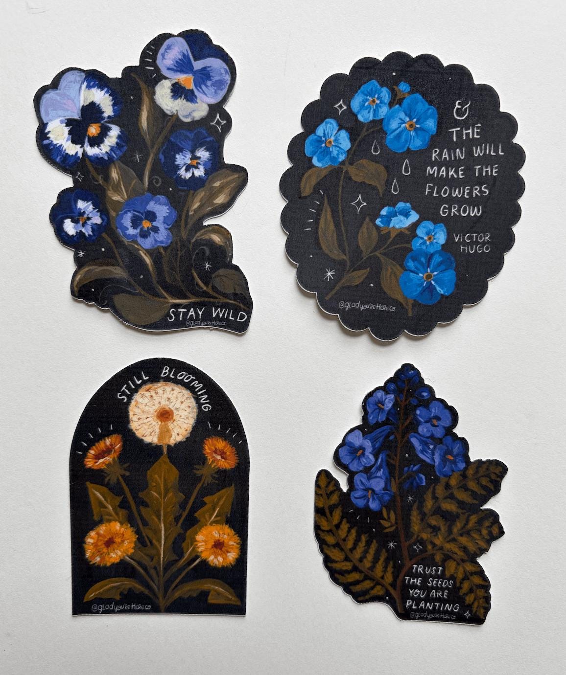 Four decorative stickers with floral designs and text on a white background