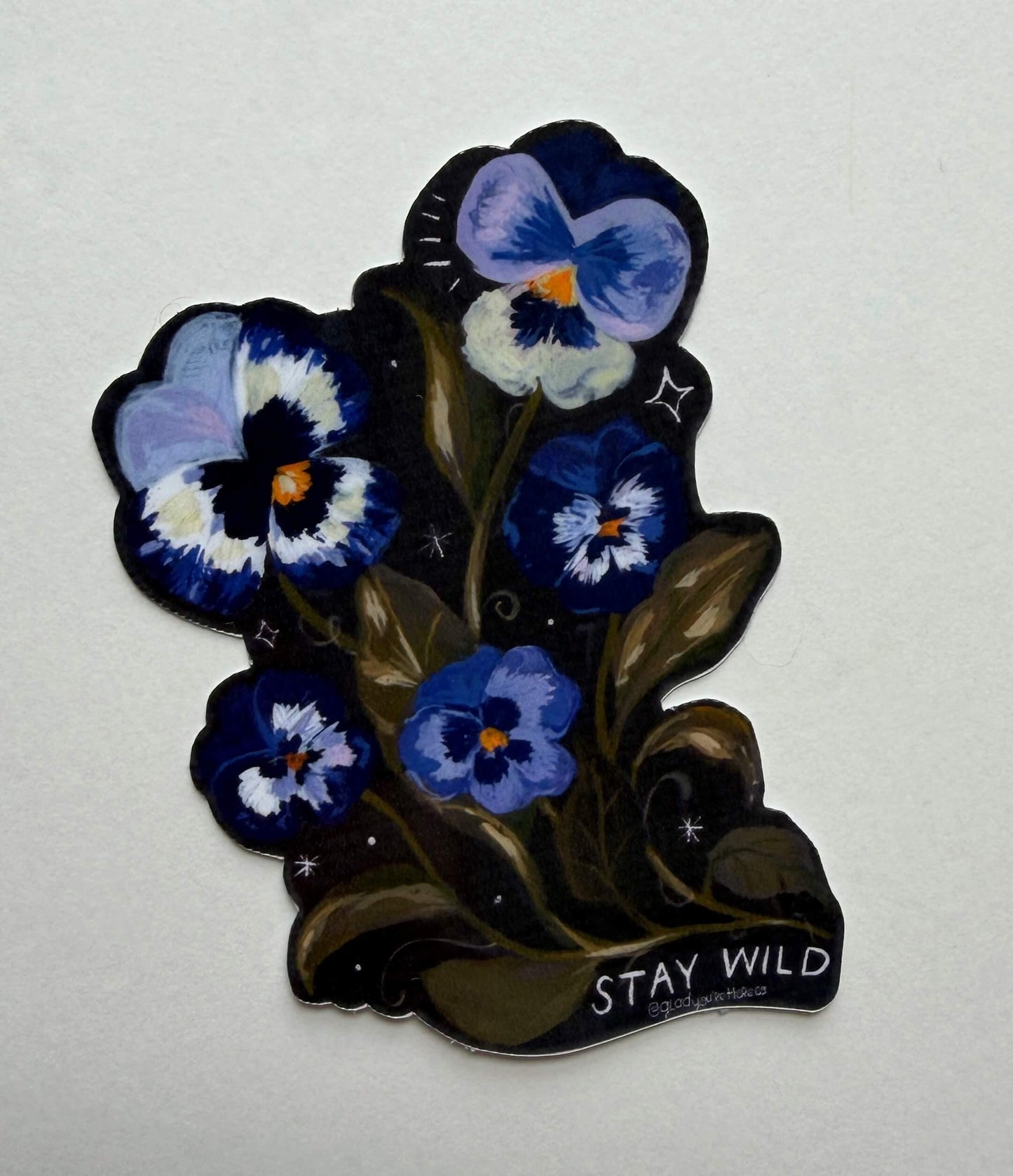 Sticker with blue and purple flowers and 'Stay Wild' text on a white background