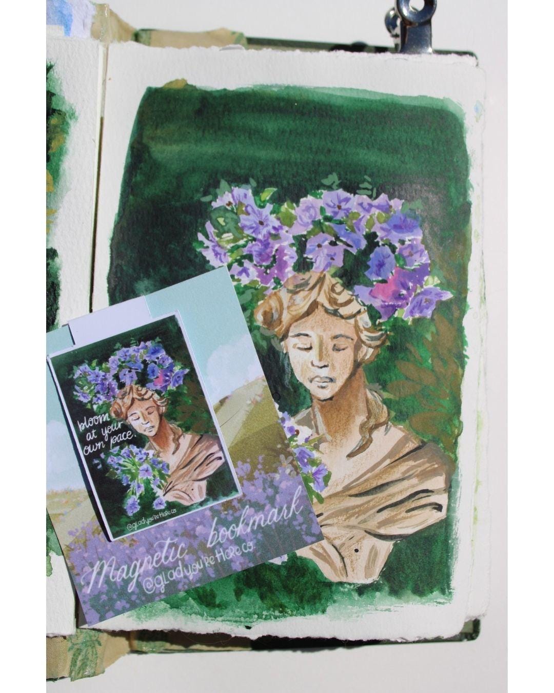 Artistic depiction of a woman with flowers in her hair, accompanied by a matching bookmark.