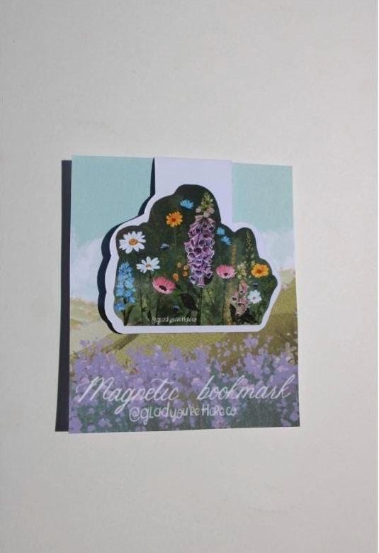 Floral bookmark with a scenic background on a light gray surface
