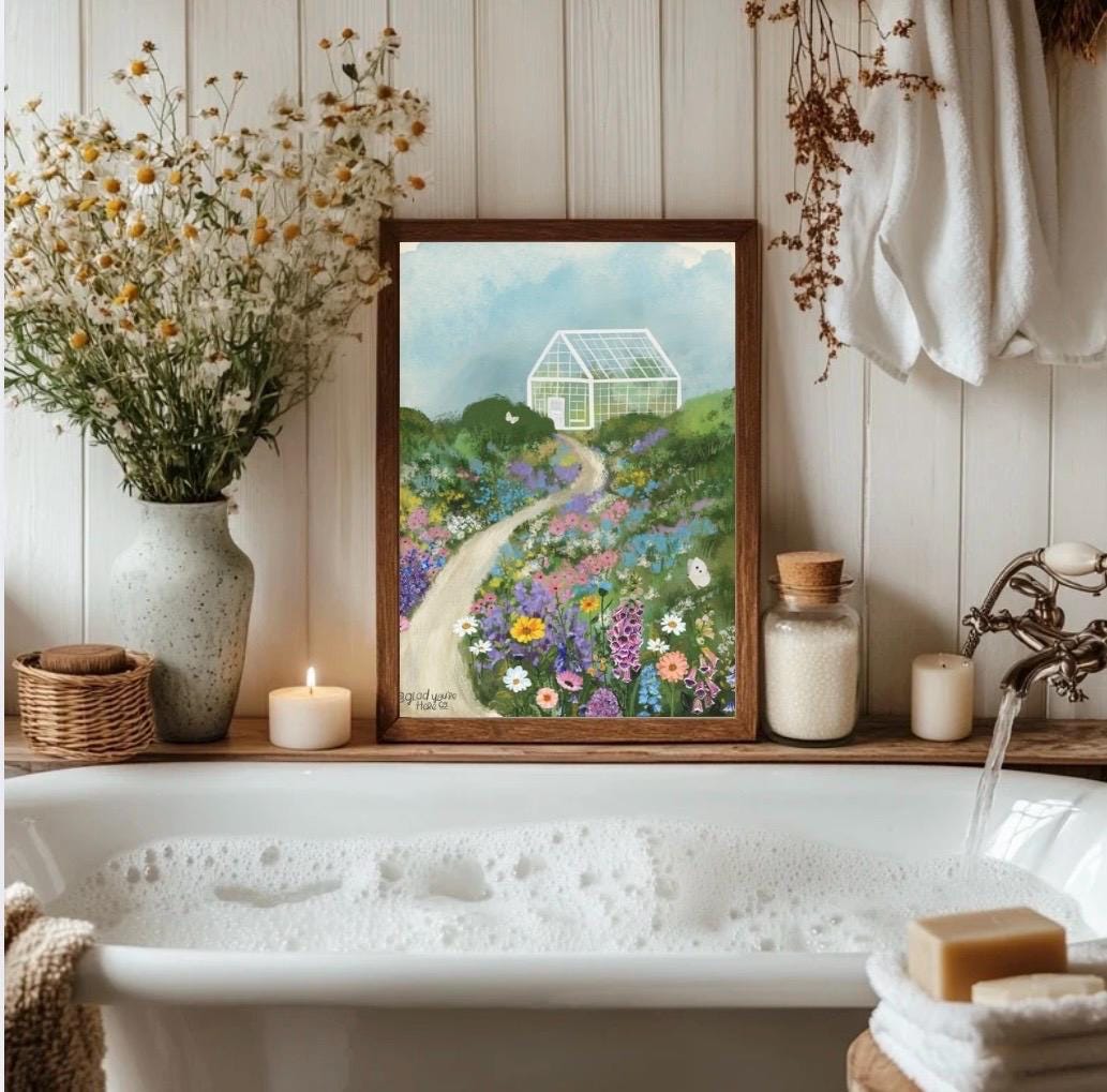 Bathroom with a bathtub, flowers, candles, and a framed painting of a garden.