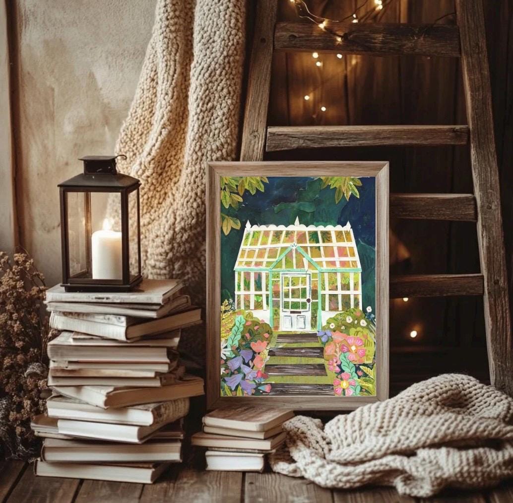 Framed collaged print of a greenhouse with books and a lantern on a wooden surface.