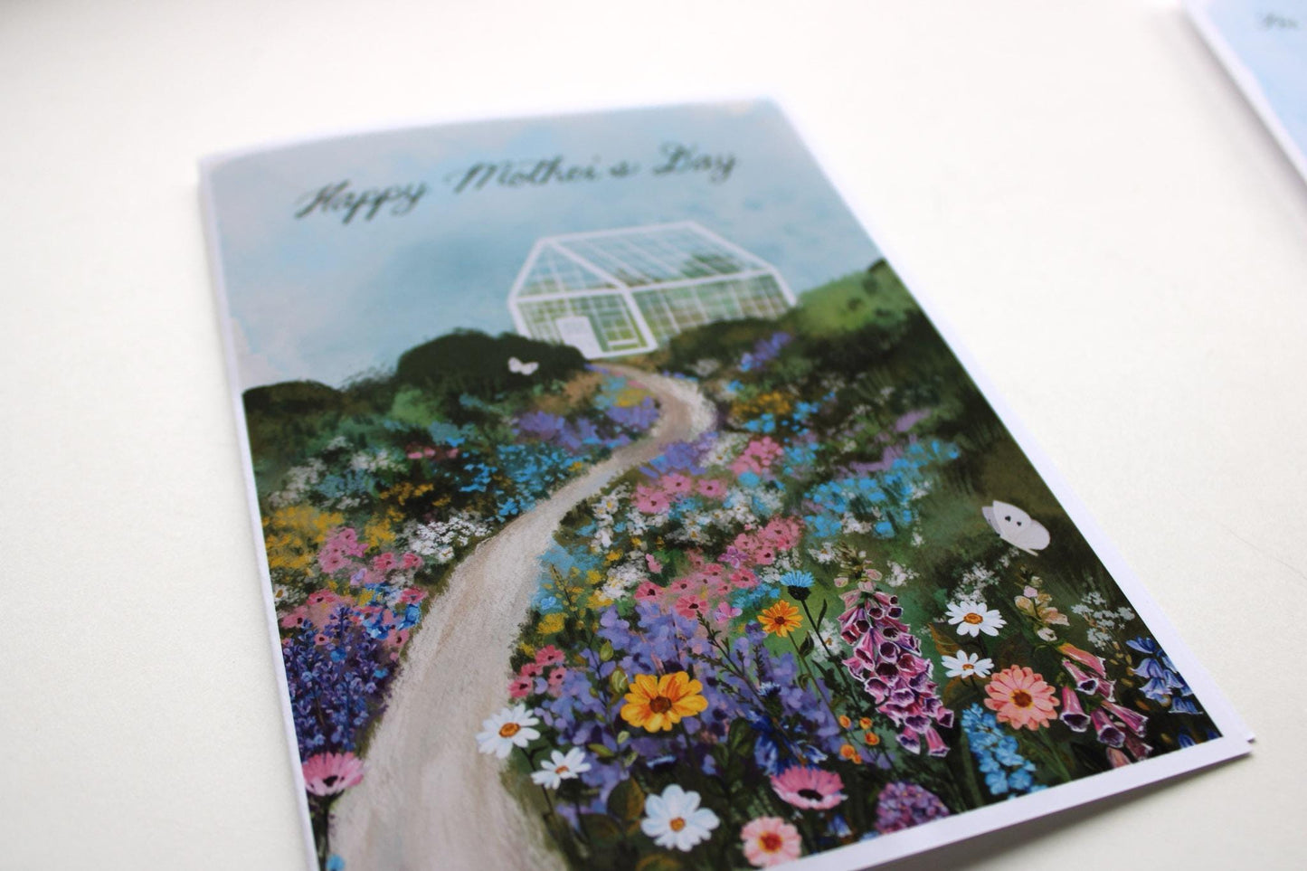 Greeting card with a garden scene and 'Happy Mother's Day' text on a white background