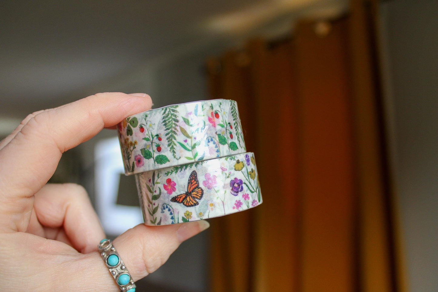 Hand holding a roll of floral tape with a blurred background