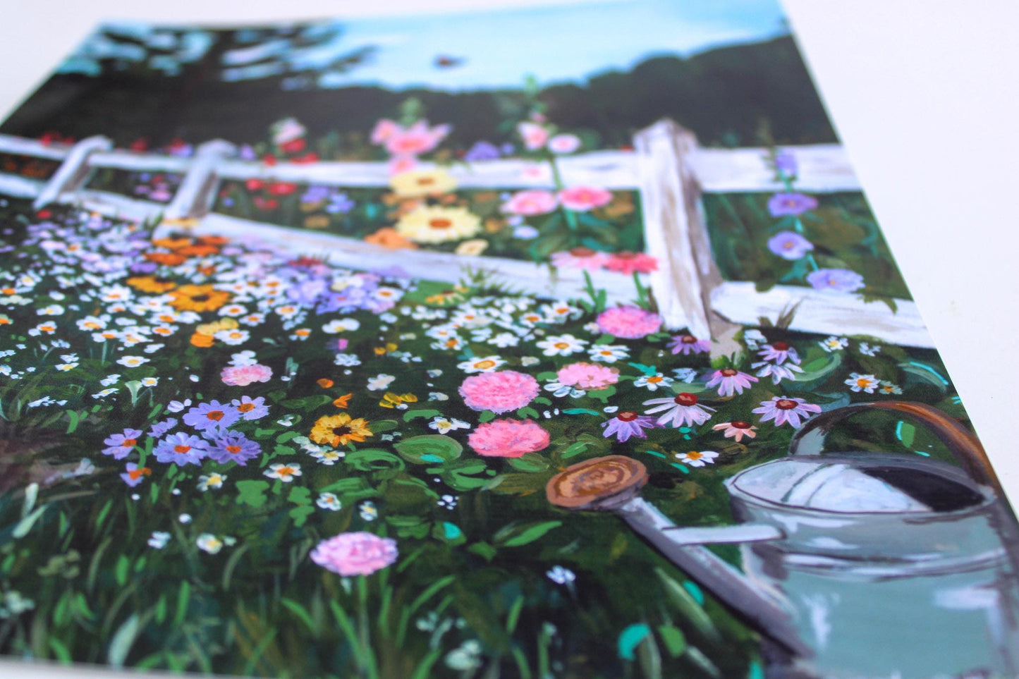 Colorful garden scene with flowers and a watering can on a printed material.