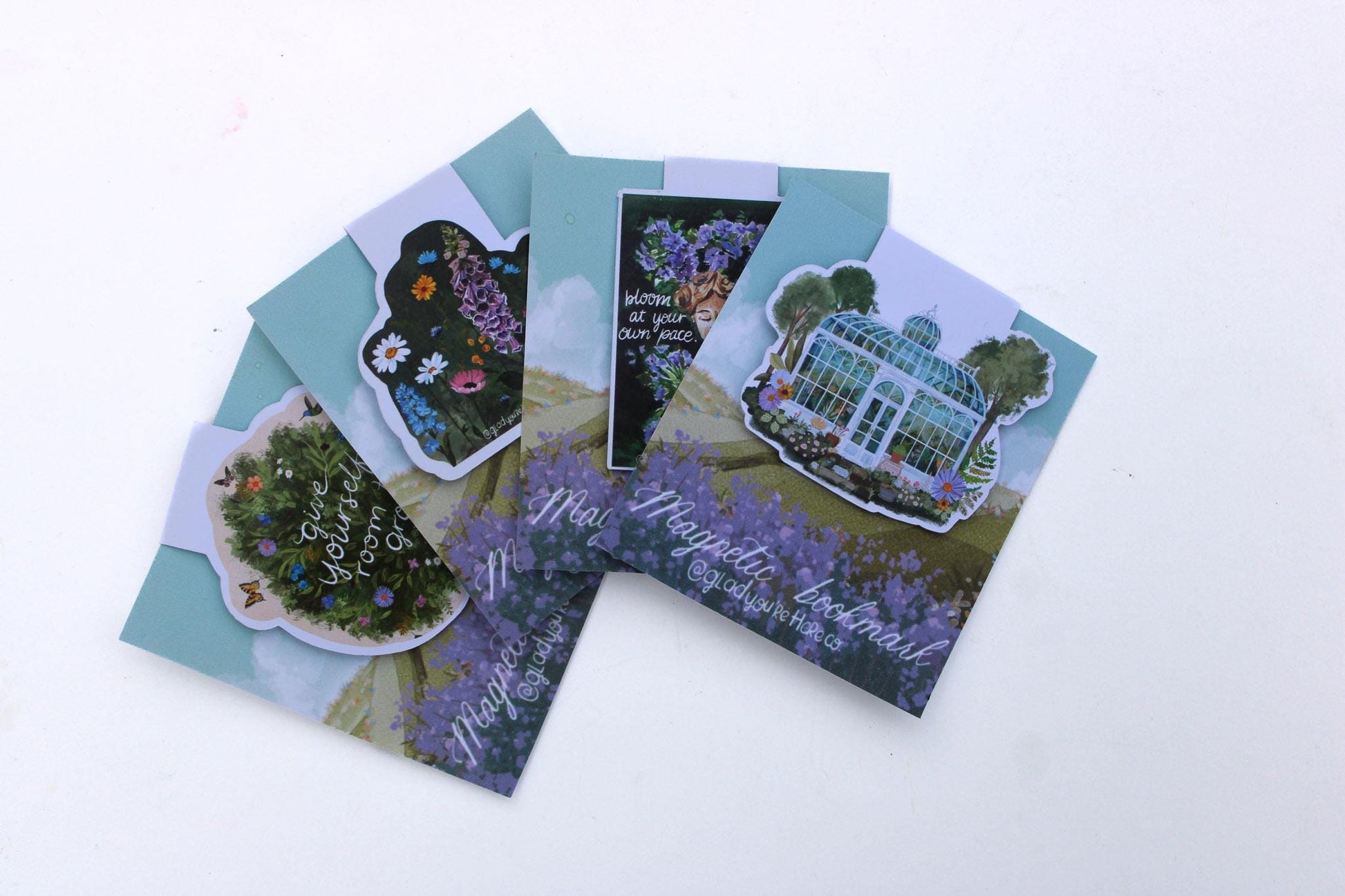 Set of four magnetic bookmarks with various garden botanical designs on a white background