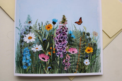 Greeting card with a colorful illustration of flowers and butterflies on a light blue background.