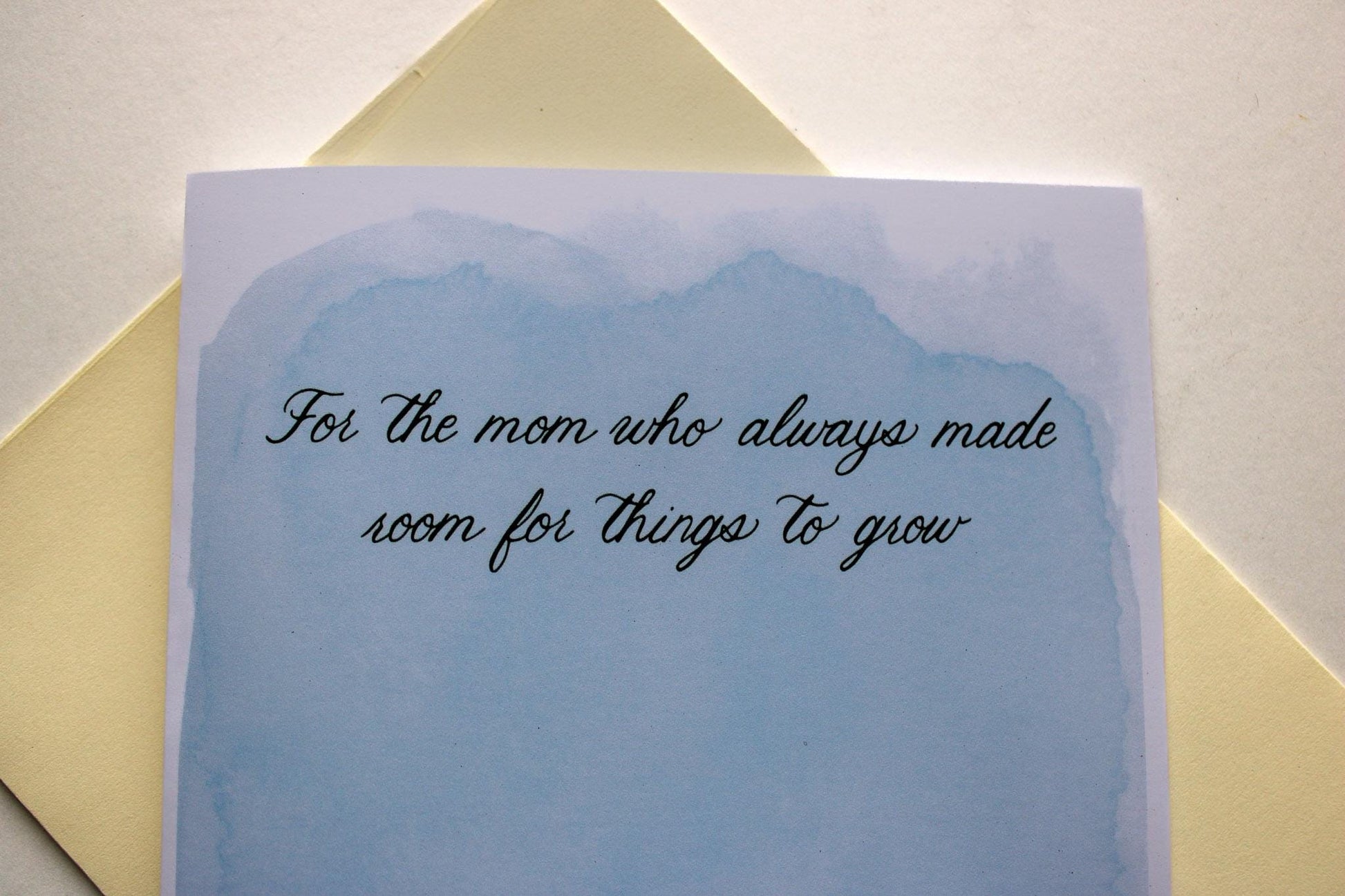 Greeting card with text on a light blue background, placed on a yellow envelope.