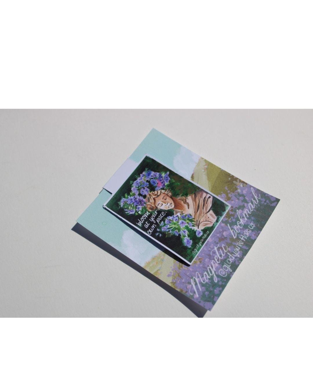 Decorative magnetic bookmark with floral design and text on a light gray background