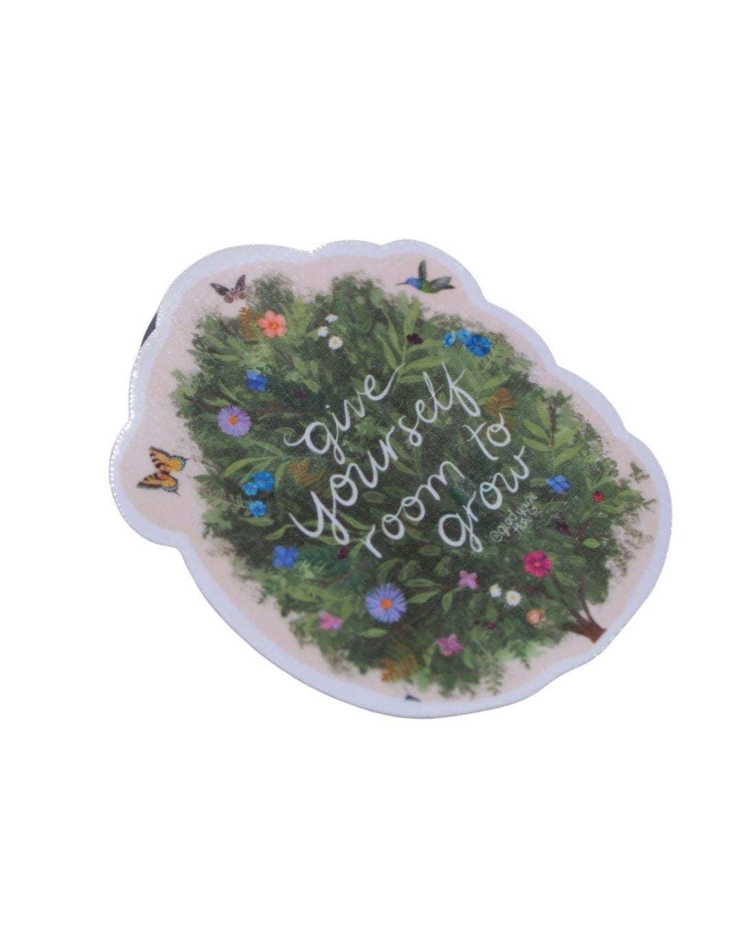 Decorative sticker with green wreath, flowers, butterflies, and text on a white background