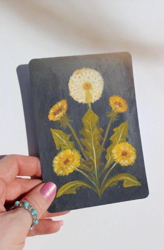 Hand holding a card with dandelion illustration on a white background