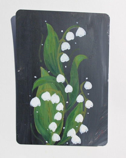 Painting of white flowers with green leaves on a dark background