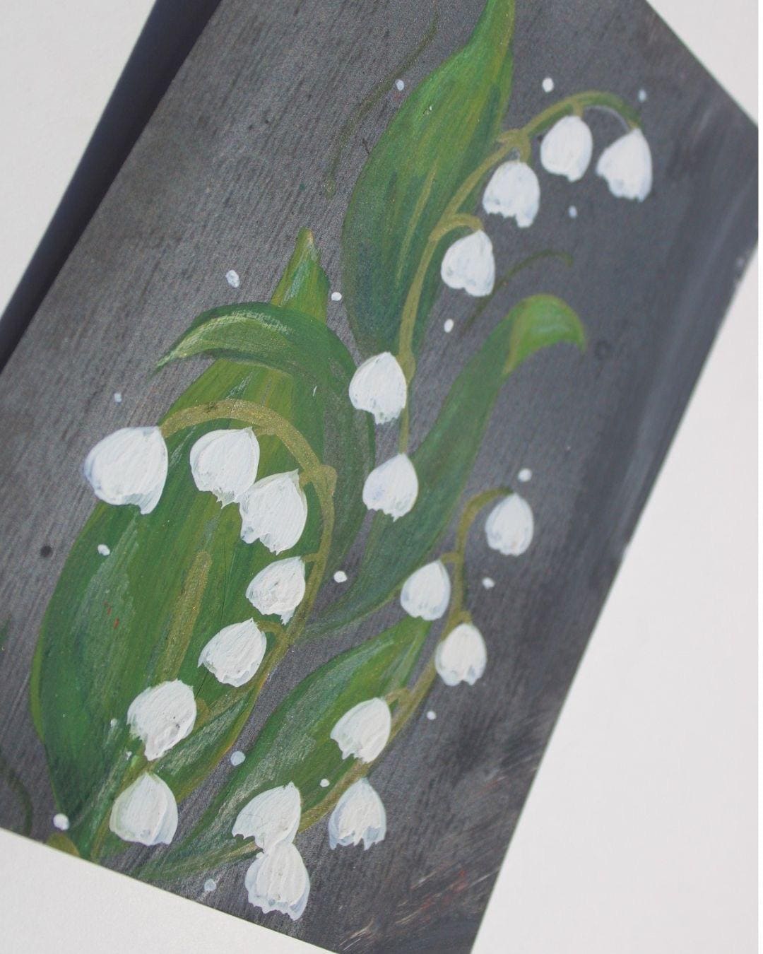 Painting of lilies of the valley on a dark background
