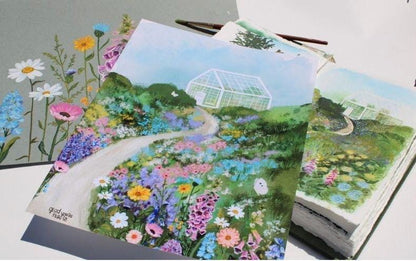 Gardening-themed greeting cards with floral designs and greenhouses on a white surface.