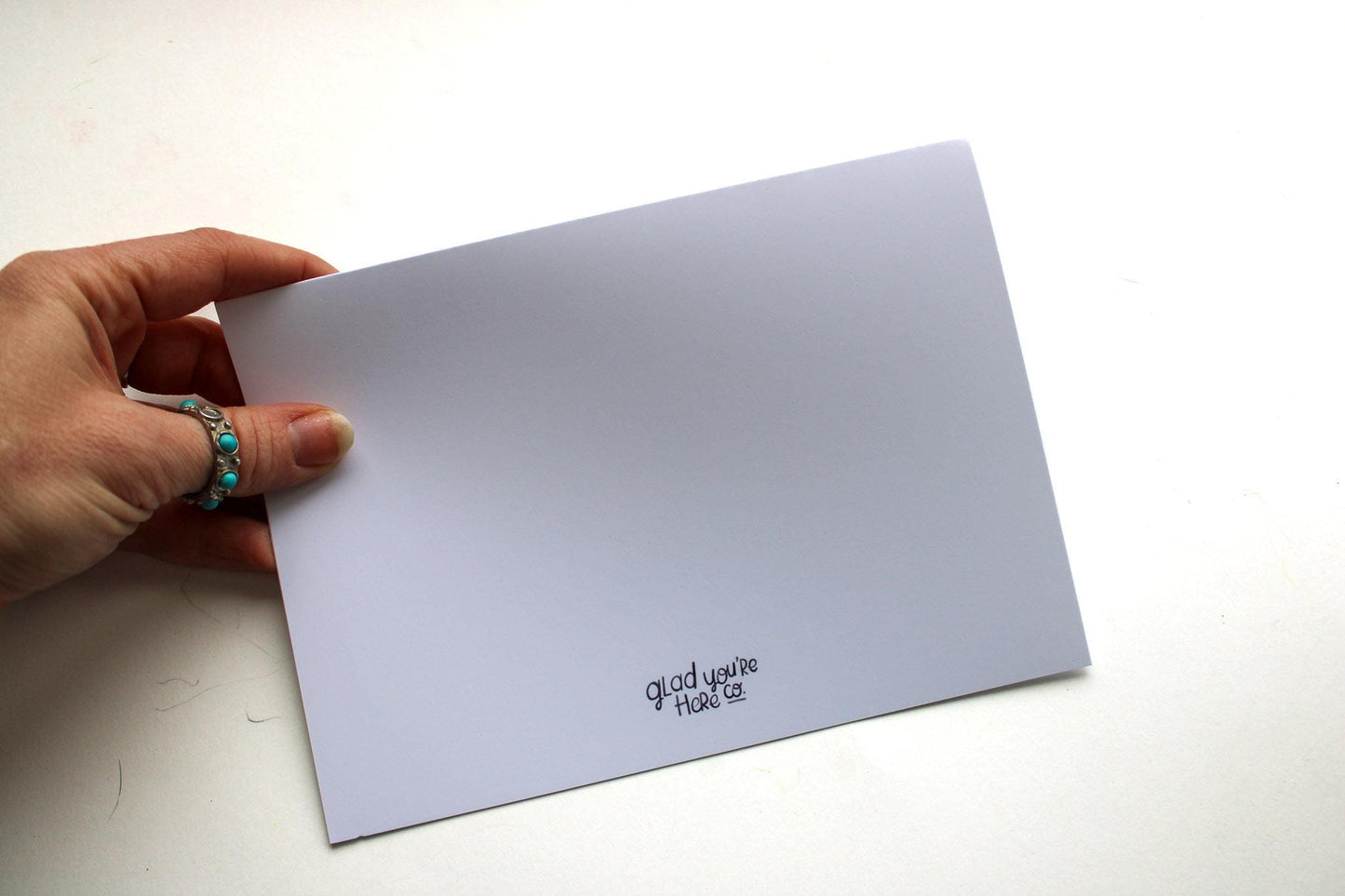 Hand holding a white card with text on a light gray background