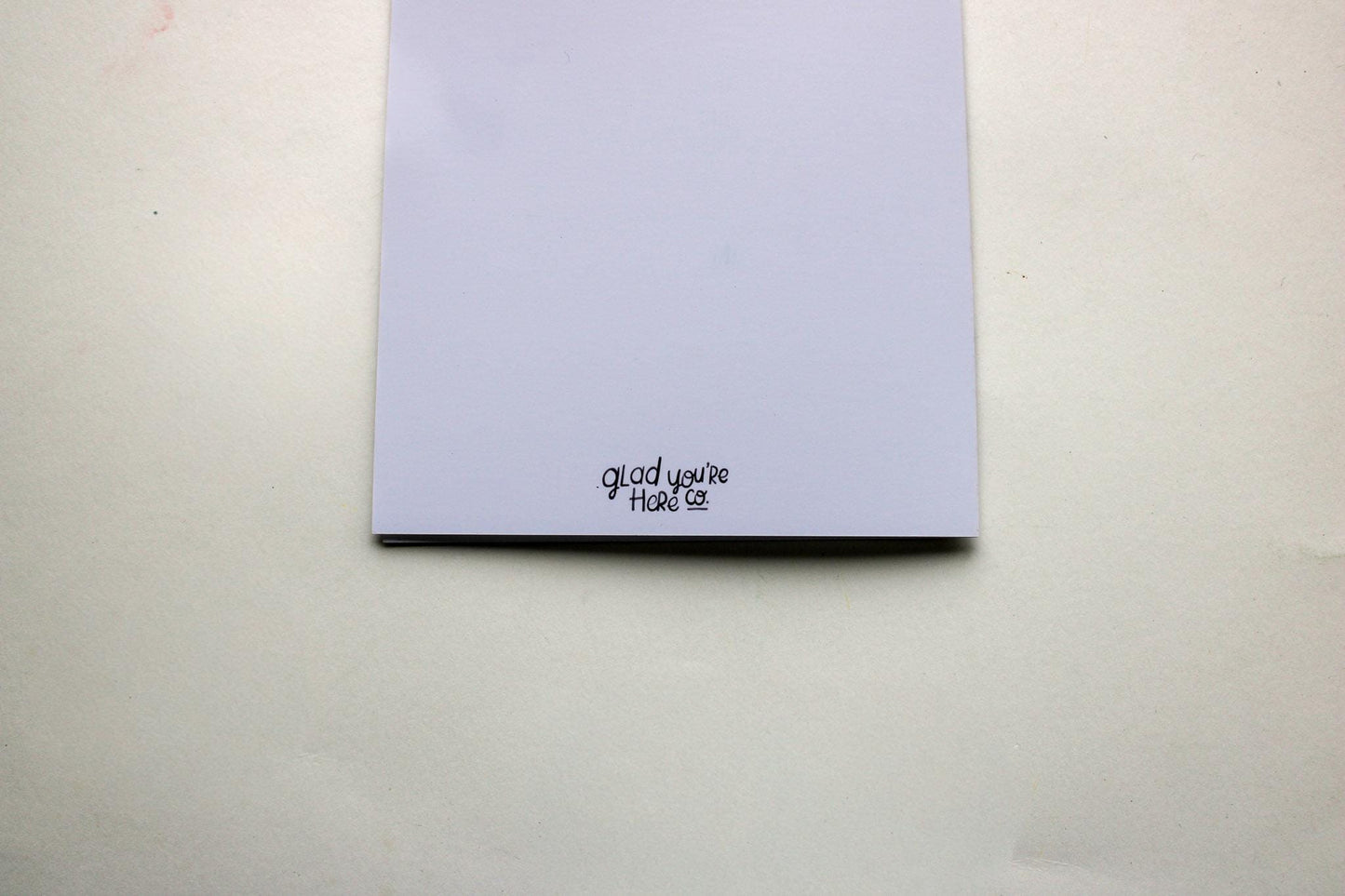 back of greeting card with 'Glad you're here co.' text on a plain background