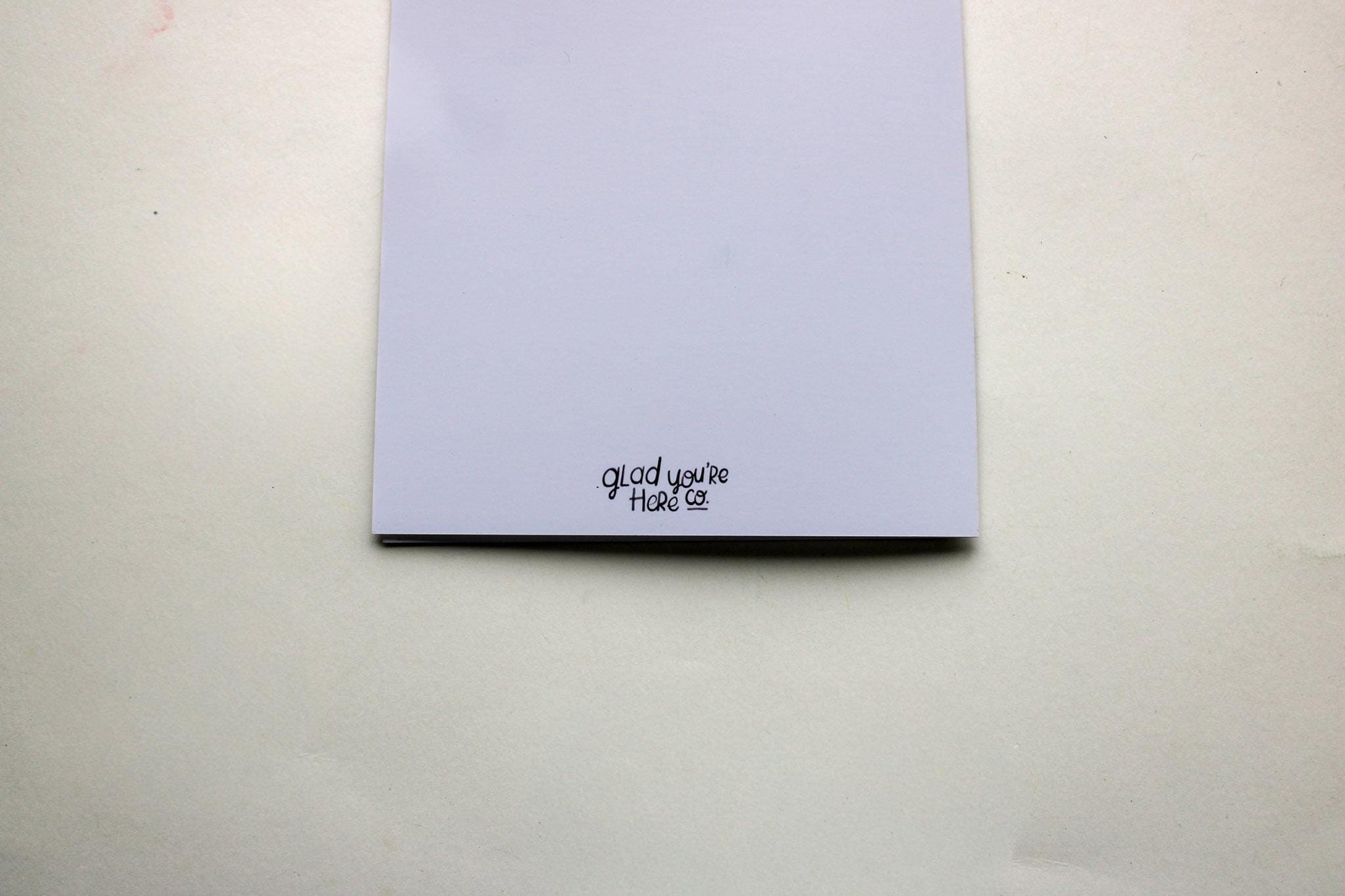 back of greeting card with 'Glad you're here co.' text on a plain background