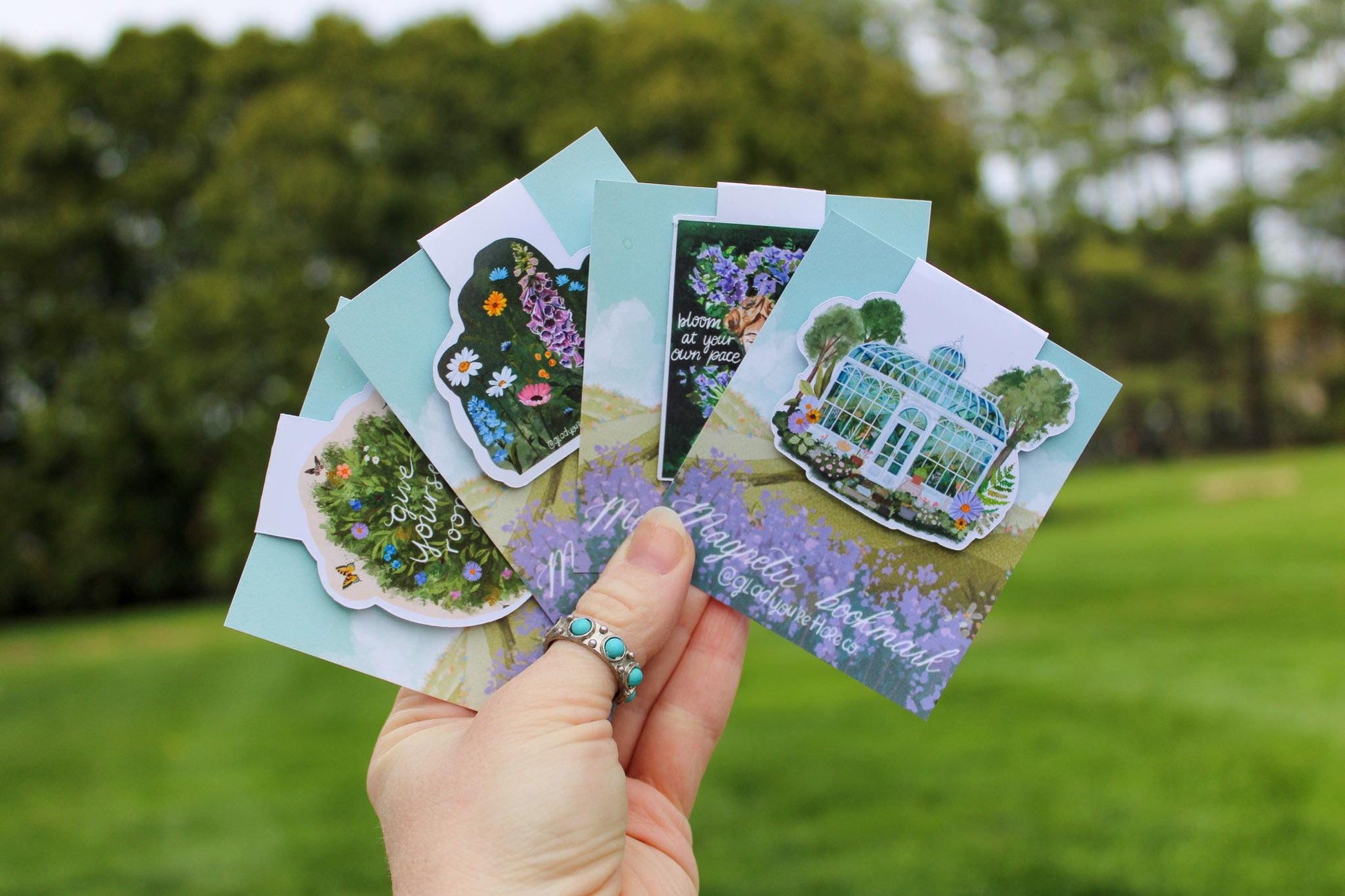 Hand holding a set of garden-themed cards with a blurred green outdoor background