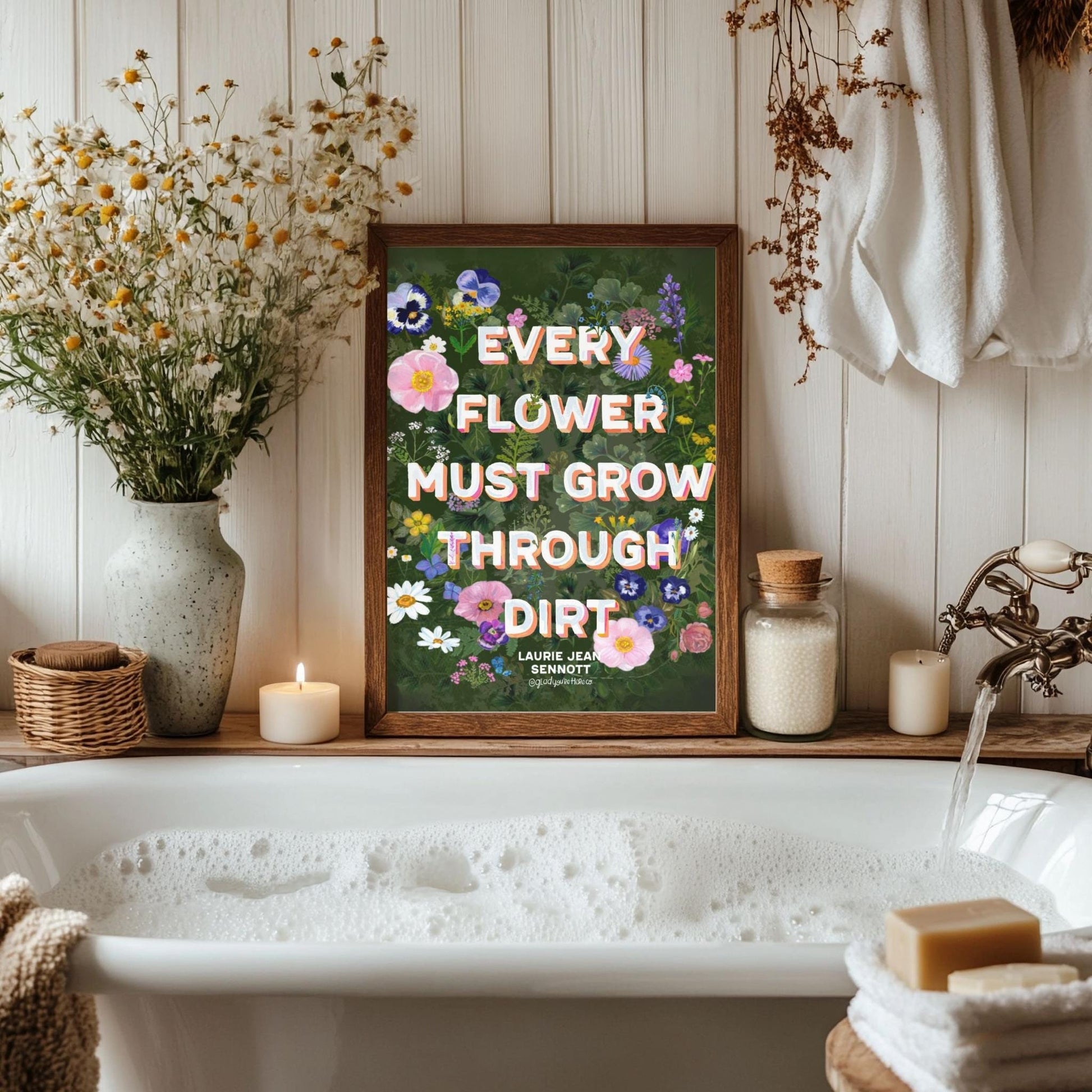Bathroom with a bathtub, flowers, and a motivational sign on a wooden shelf.