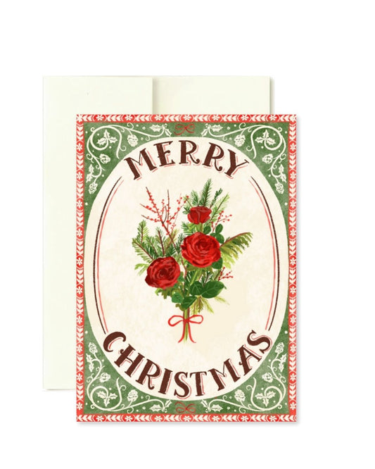 A vintage-style Christmas greeting card with an envelope behind it. The card features the words “MERRY CHRISTMAS” in arched brown lettering around a bouquet of red roses, green foliage, and berries, set within an oval frame with a decorative red and green border.