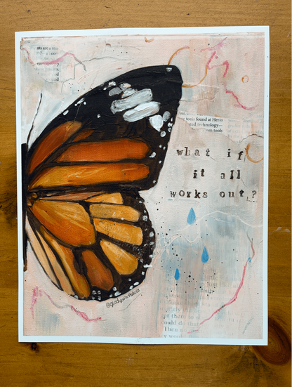 An art print featuring a painted monarch butterfly on a textured, collage-style background with the text 'what if it all works out?' and blue raindrop accents, displayed on a wooden surface.
