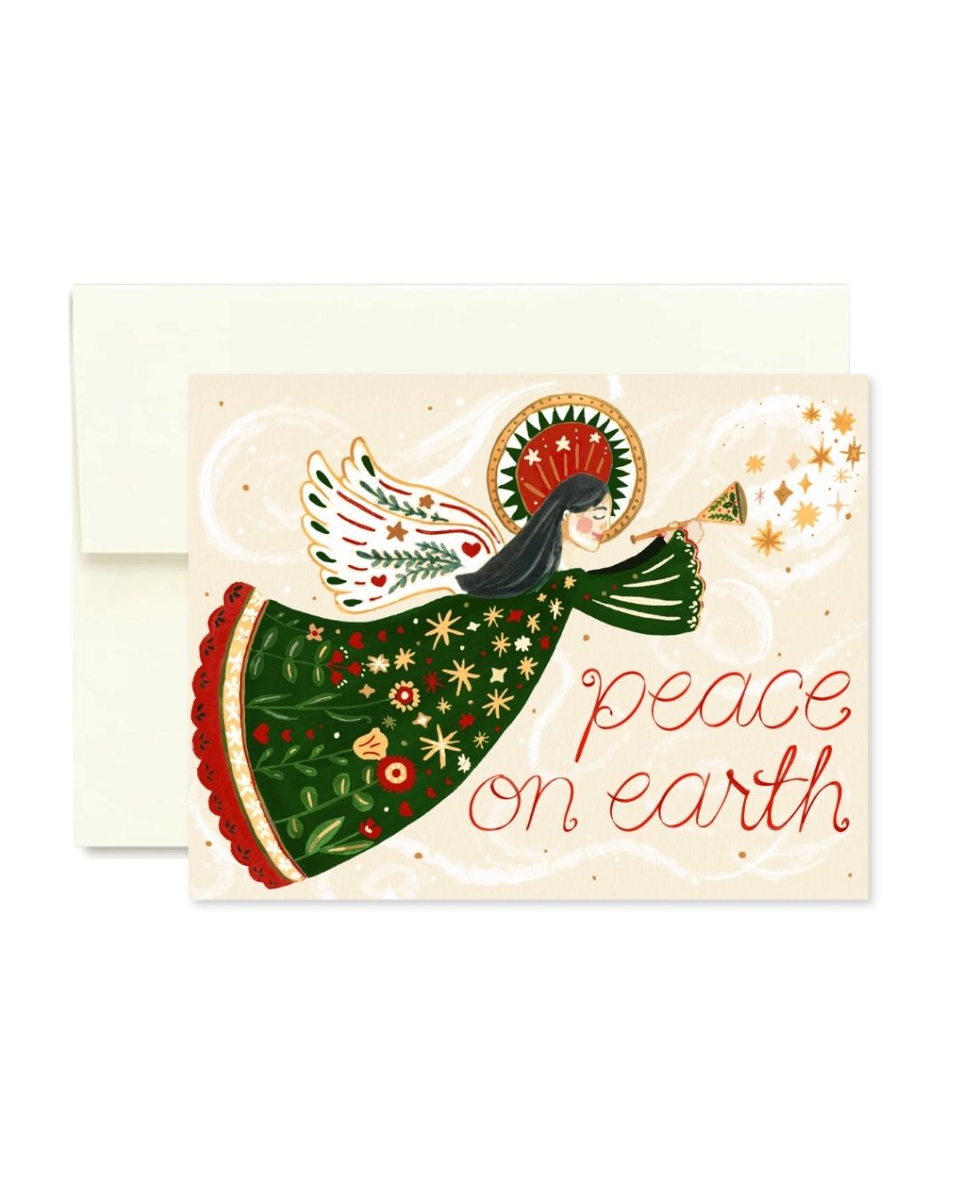 A Christmas greeting card with an illustrated angel in a green patterned dress blowing a trumpet, with the words 'peace on earth' in red script, shown with a cream envelope behind it on a white background.