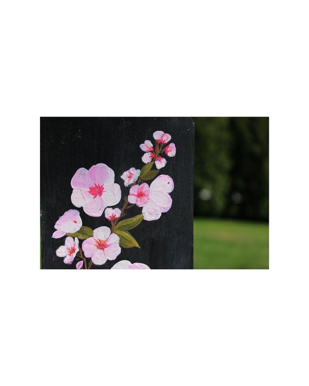 Floral design on a black background with pink flowers and green leaves.