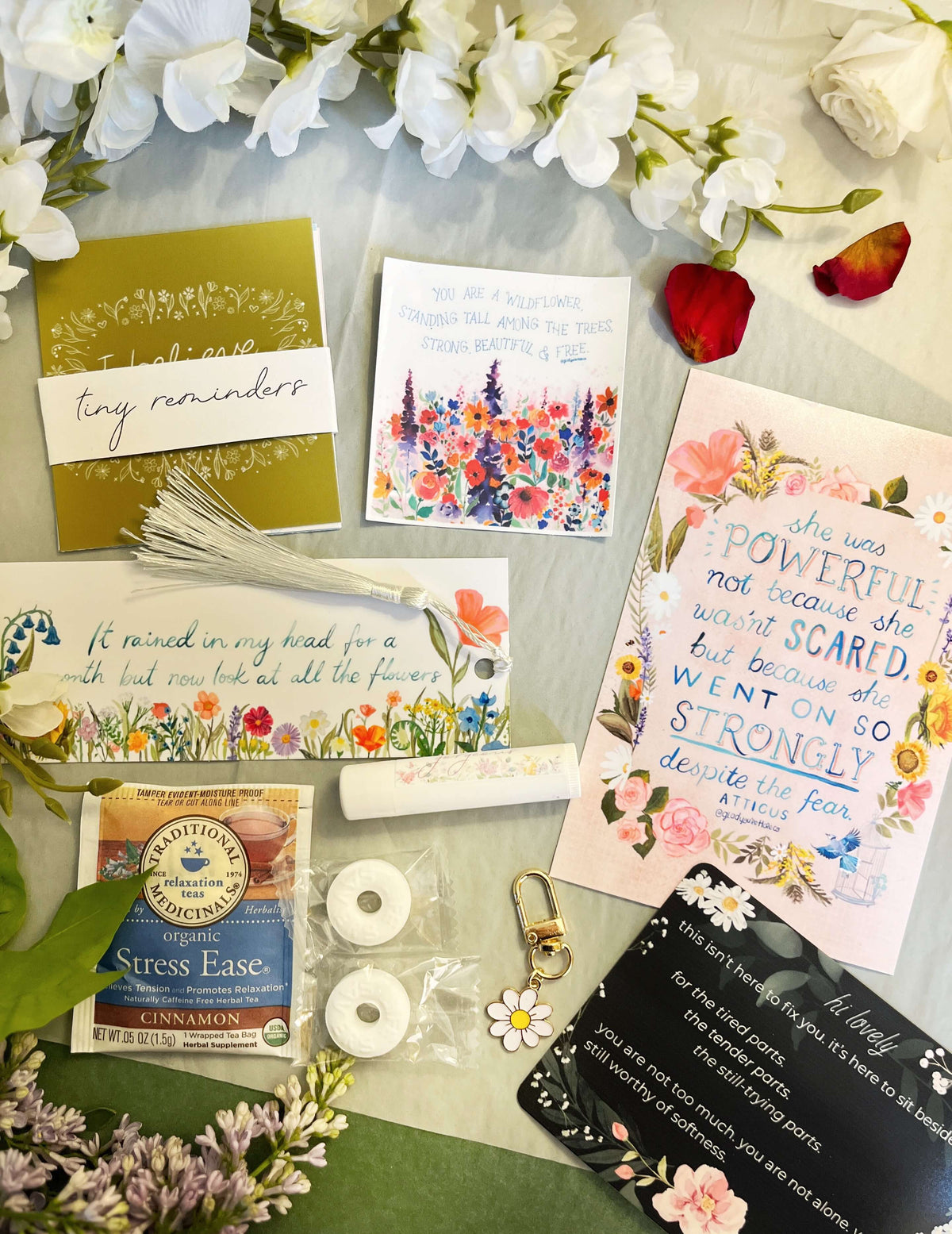 Collection of cards, a stress relief product, and decorative items on a surface with flowers.