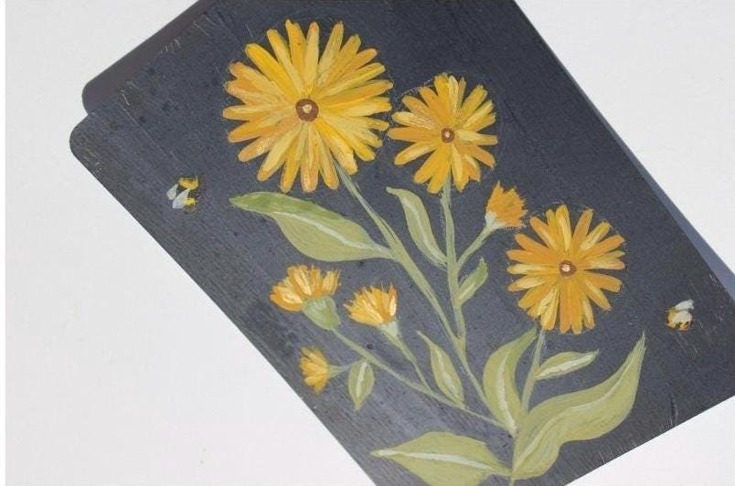Decorative slate tile with yellow floral design on a white background