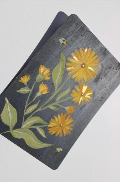 Floral design on a dark surface with yellow flowers and green leaves.